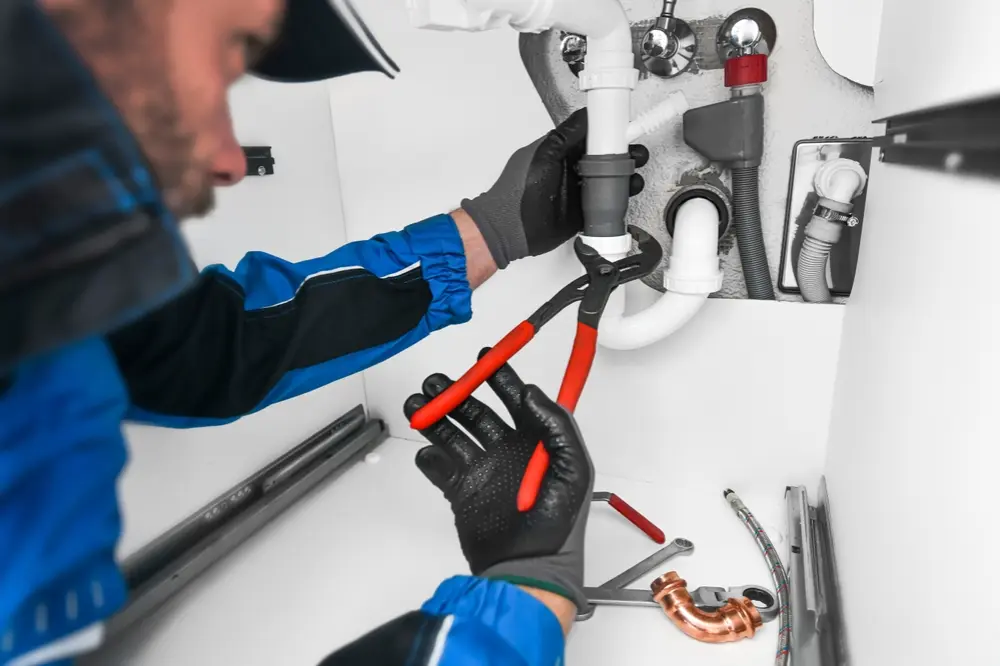 Poly-B technician repairing a copper water pipe inside a residential wall