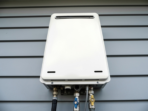 Plumber inspecting Poly-B piping connected to a residential water heater installation