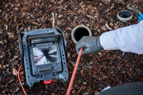 Poly-B technician feeding a waterproof inspection camera into a residential drain pipe in Orillia