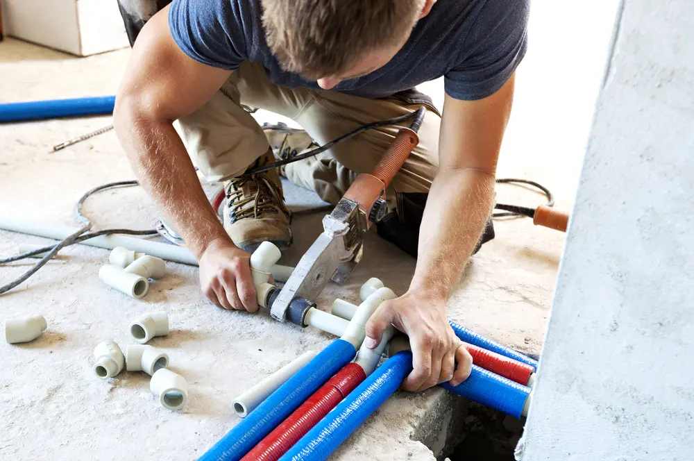 Plumber discussing plans with a general contractor and property manager on a job site