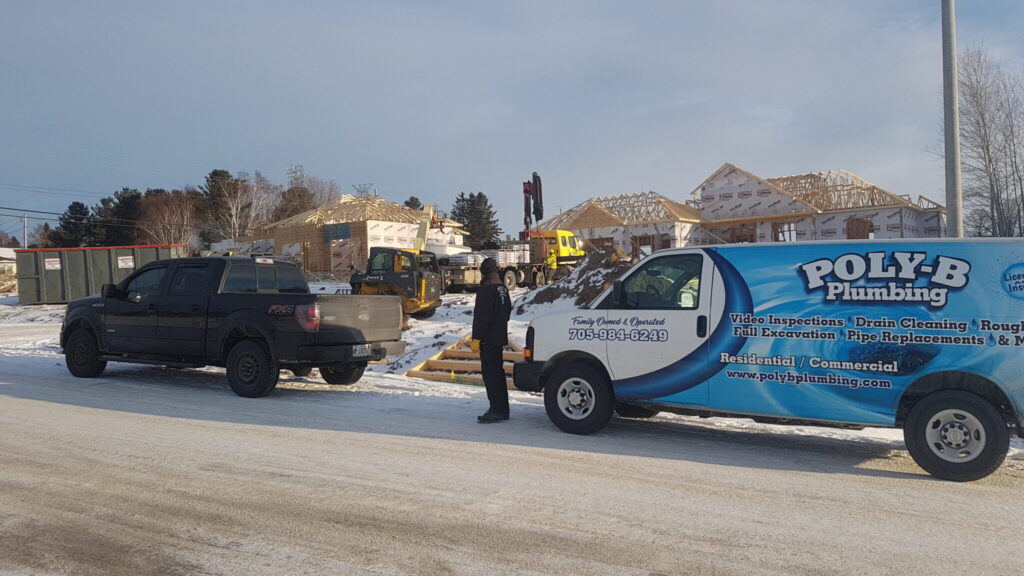 Founding team member of Poly-B Plumbing standing in front of a service van in Orillia or North Bay