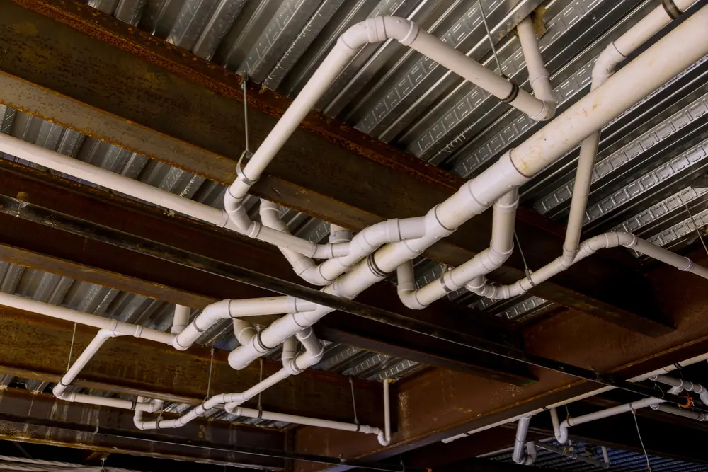 Plumber collaborating with a contractor and business owner on a commercial construction site