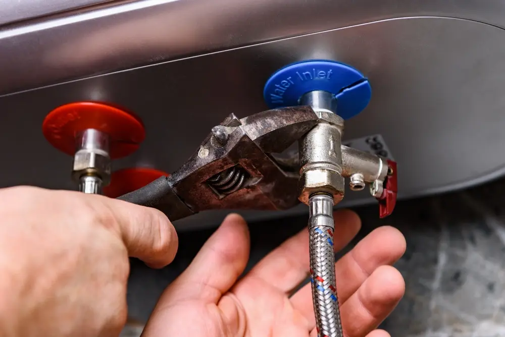 Poly-B technician examining the thermostat and pressure valve on a home water heater
